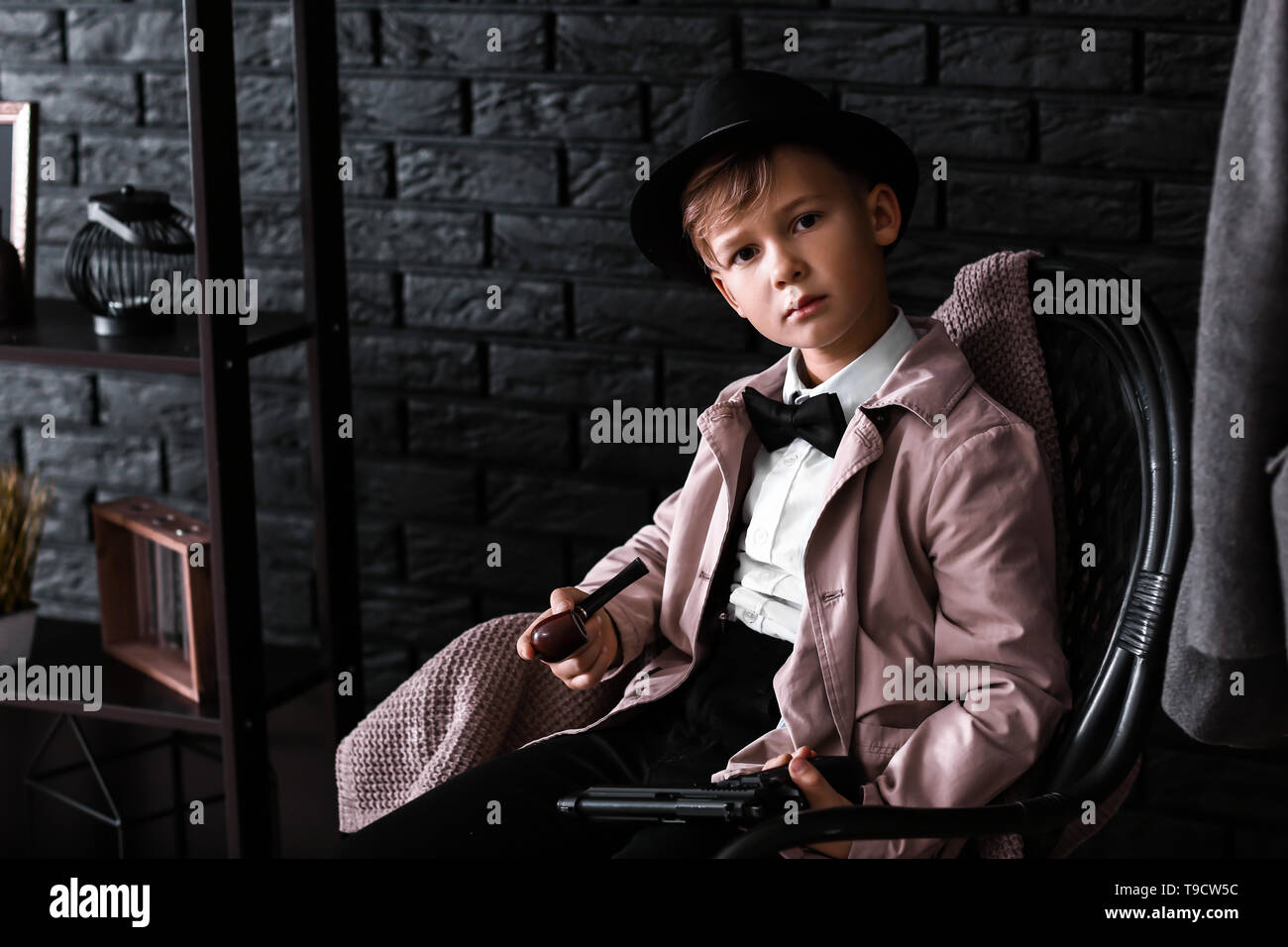 Cute little detective avec tuyau sitting in armchair Banque D'Images
