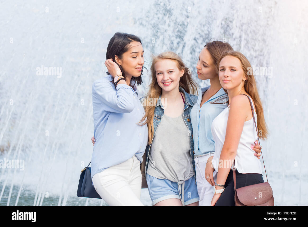 Les jeunes filles composite parler près de la fontaine dans la ville sur une chaude journée Banque D'Images