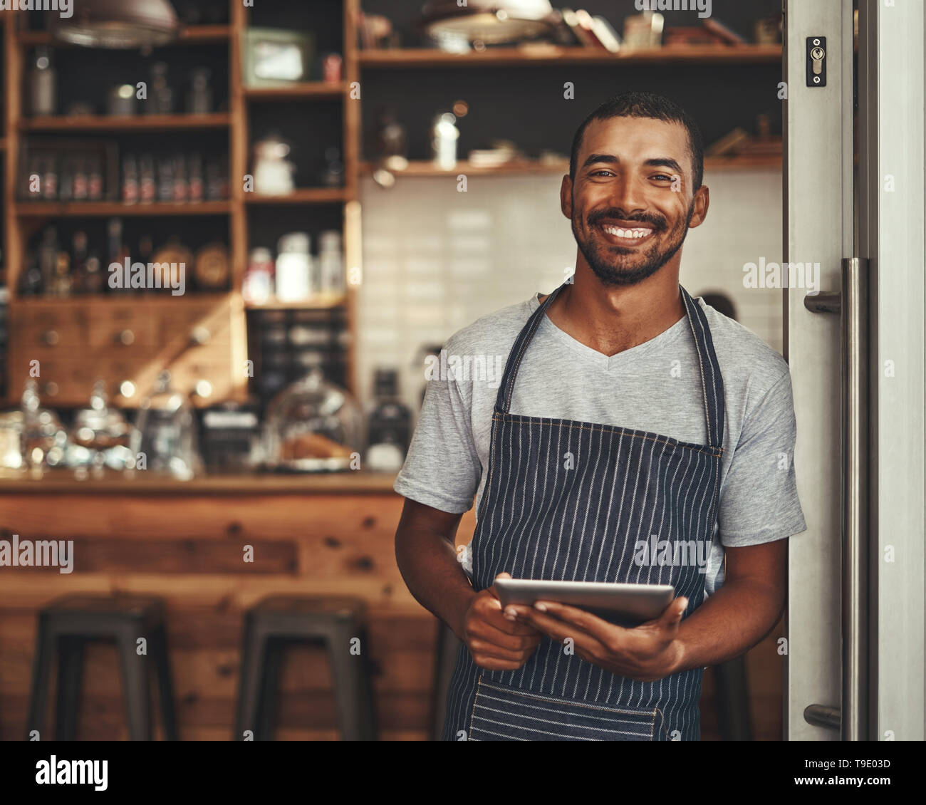 Portrait of a male owner holding digital tablet dans son cafe Banque D'Images