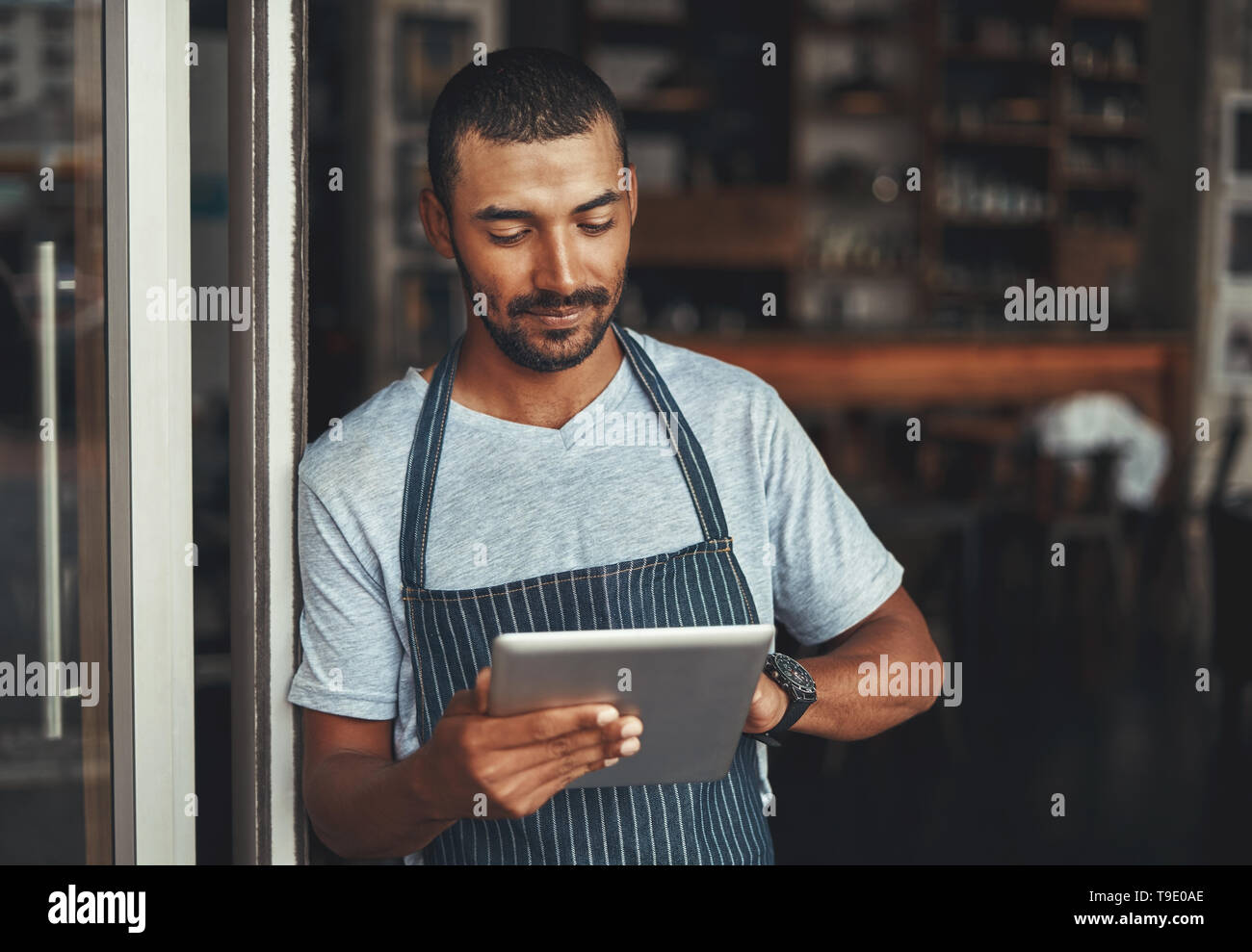 Jeune homme cafe owner using digital tablet Banque D'Images