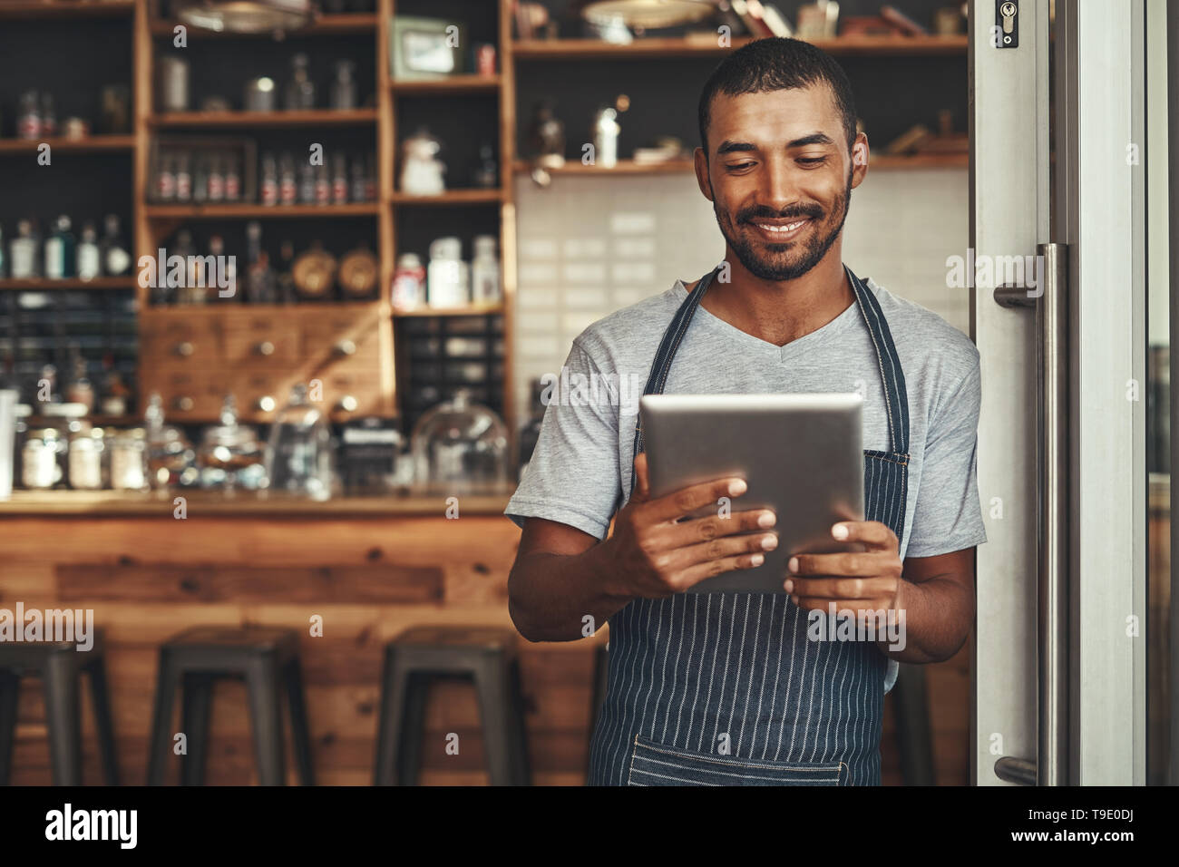 Jeune homme cafe owner looking at digital tablet Banque D'Images