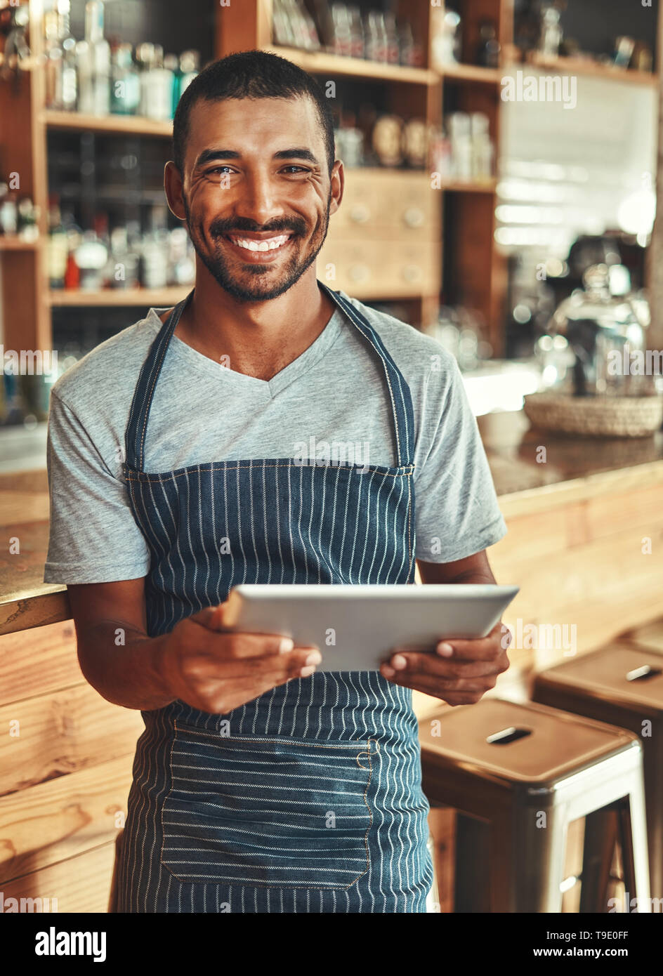 Portrait of smiling male cafe owner holding digital tablet Banque D'Images
