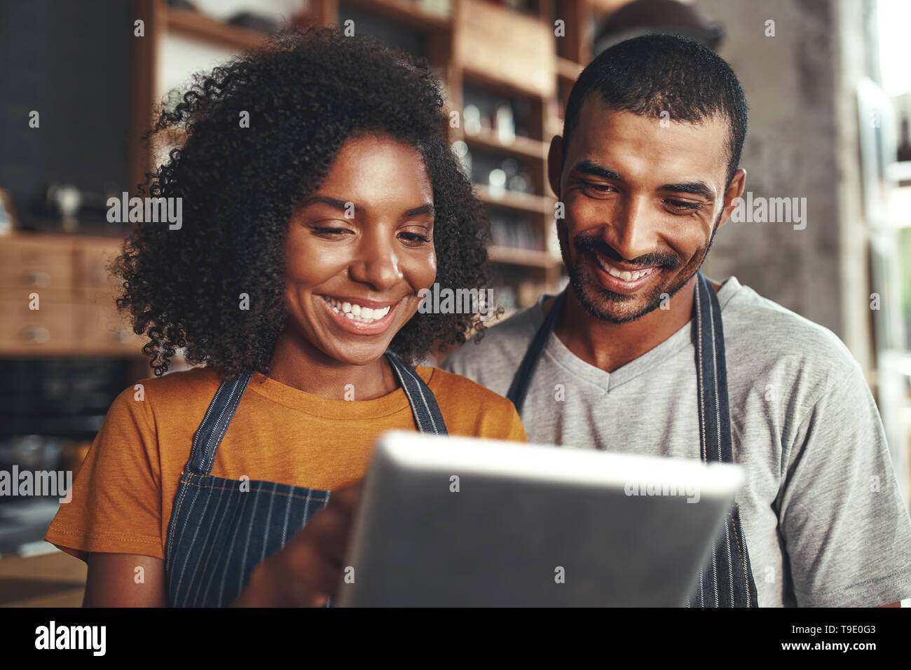 Smiling cafe owner in apron looking at digital tablet Banque D'Images