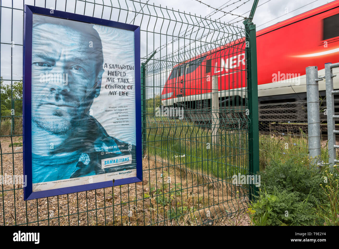 Samaritains poster 'un Samaritain m'a aidé à prendre le contrôle de ma vie' à un passage à niveau sur le chemin de fer de ligne principale de la côte est. Banque D'Images