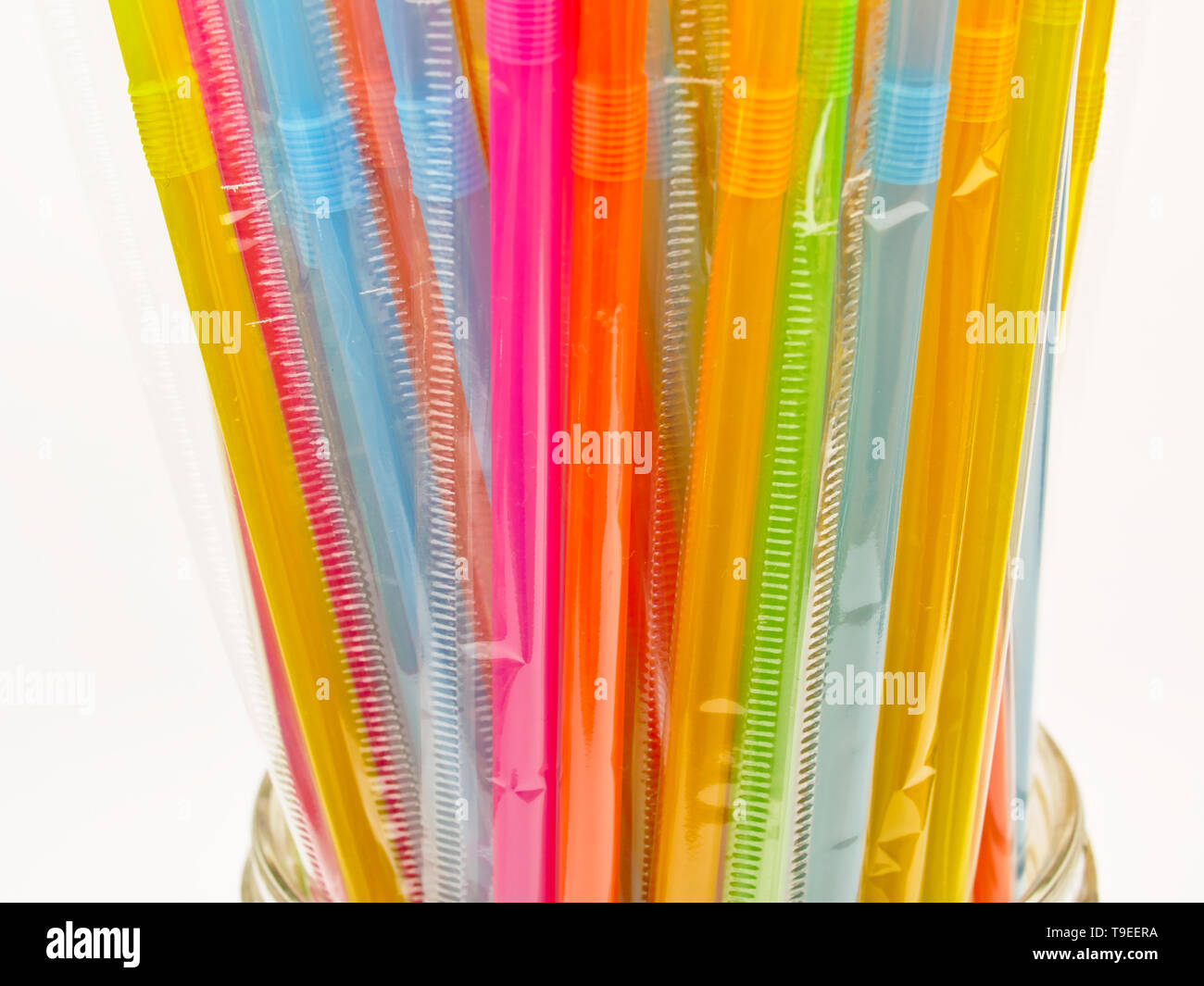 Beaucoup de pailles en plastique multicolore dans un bol en verre. Isolé sur fond blanc. Des pailles en plastique sont interdits dans plusieurs pays du monde. Banque D'Images