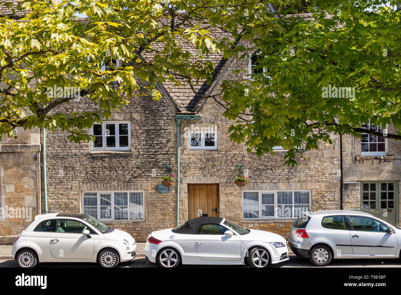 Maisons anciennes en pierre et de nouvelles voitures sur le marché de l'ancienne ville de Cotswold Northleach, Gloucestershire UK Banque D'Images