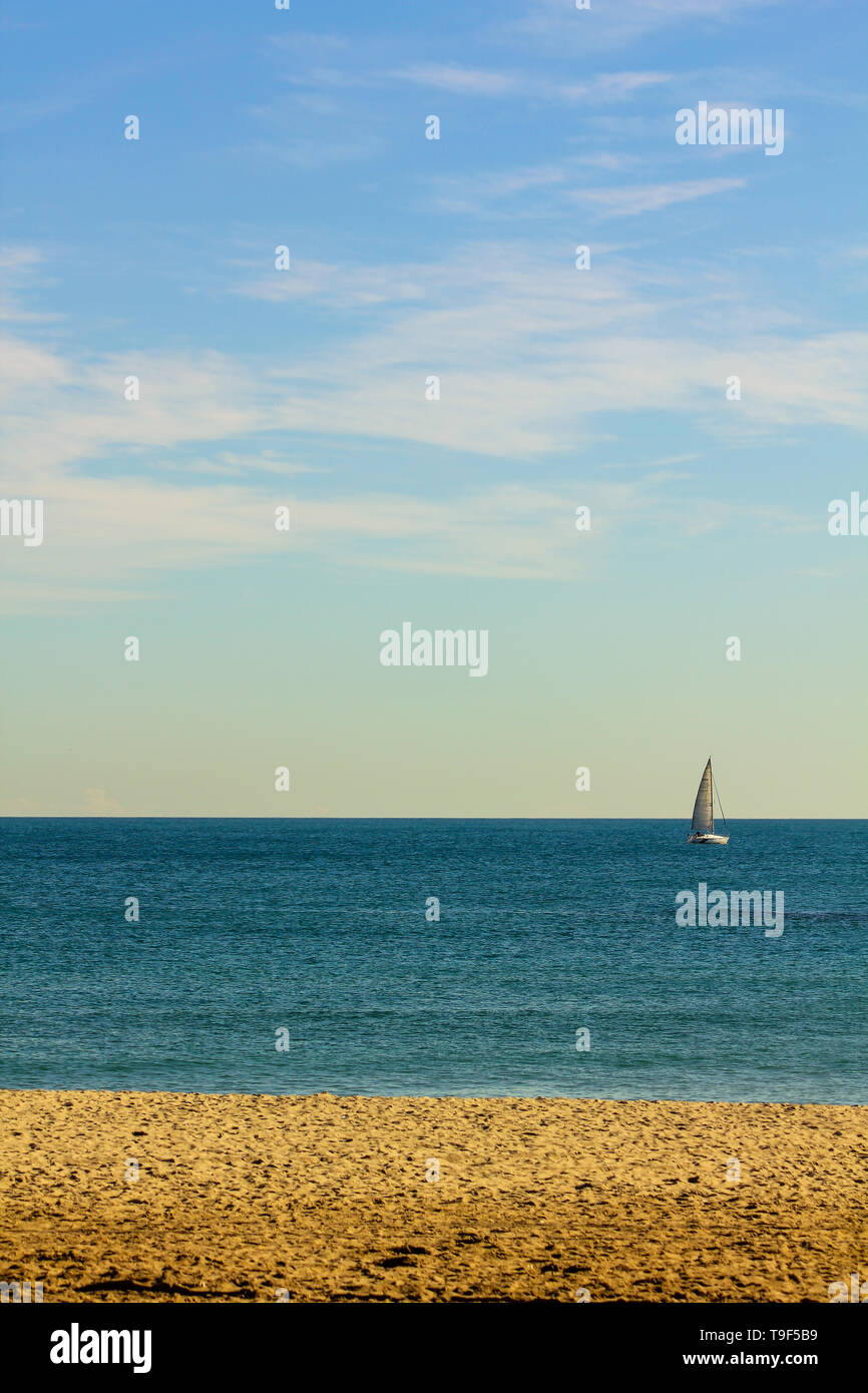 Un voilier au loin sur la plage de Barcelone, Catalogne Espagne Banque D'Images
