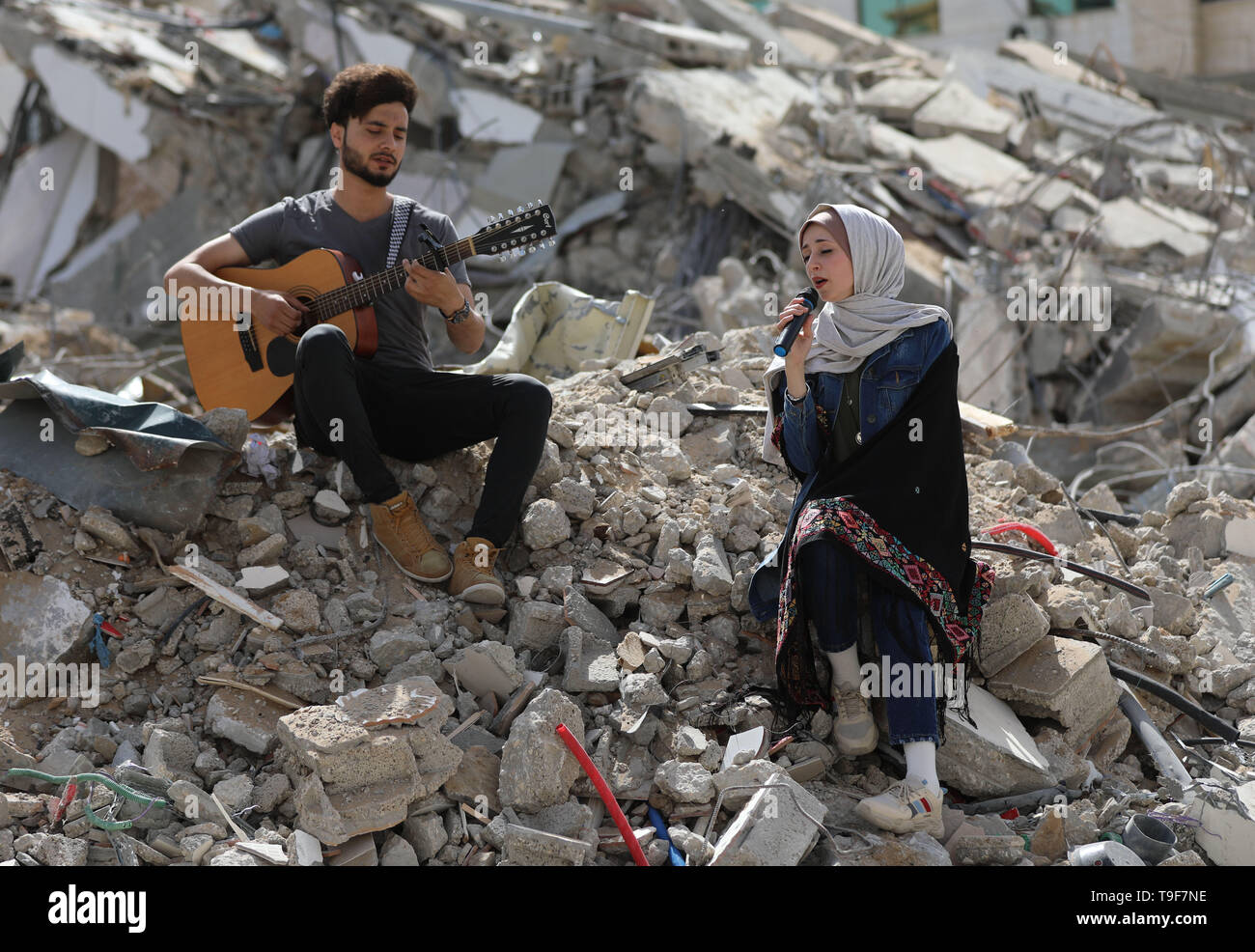 La bande de Gaza. 18 mai, 2019. Les artistes palestiniens effectuer sur les décombres d'un bâtiment qui a été récemment détruit par les frappes aériennes israéliennes, dans la ville de Gaza, le 18 mai 2019. Sur les ruines d'un bâtiment résidentiel dans la bande de Gaza détruit par des avions de guerre israéliens, un groupe de chanteurs palestiniens le samedi a envoyé un message anti-israélien de l'Eurovision qui se tiendra en Israël. Credit : Yasser Qudih/Xinhua/Alamy Live News Banque D'Images