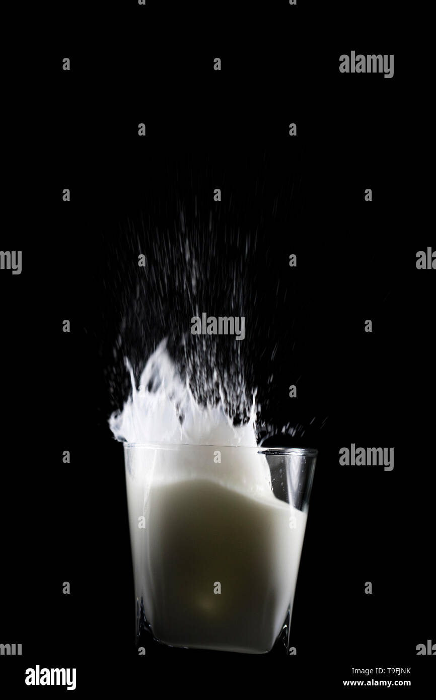 Verser un verre de lait frais blanc. La création d'un liquide grande vague. Lait renversé dans le mouvement lent de la pulvérisation d'un verre. Banque D'Images Verser un verre de lait frais blanc. La création d'un liquide grande vague. Lait renversé dans le mouvement lent de la pulvérisation d'un verre. Banque D'Images