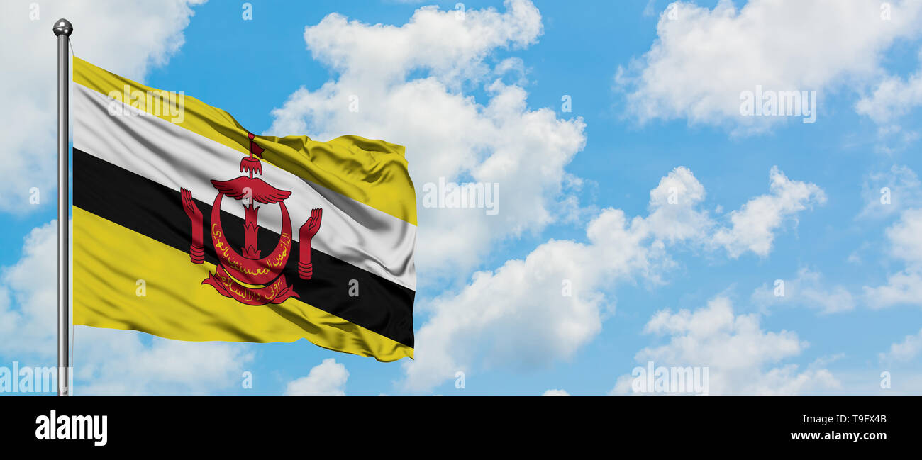 Brunei drapeaux dans le vent contre blanc nuageux ciel bleu. Concept de diplomatie, de relations internationales. Banque D'Images