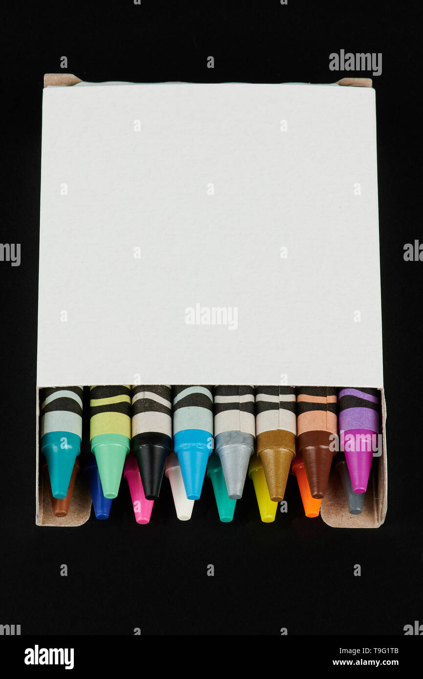 Boîte blanche avec des crayons colorés isolé sur fond noir Banque D'Images