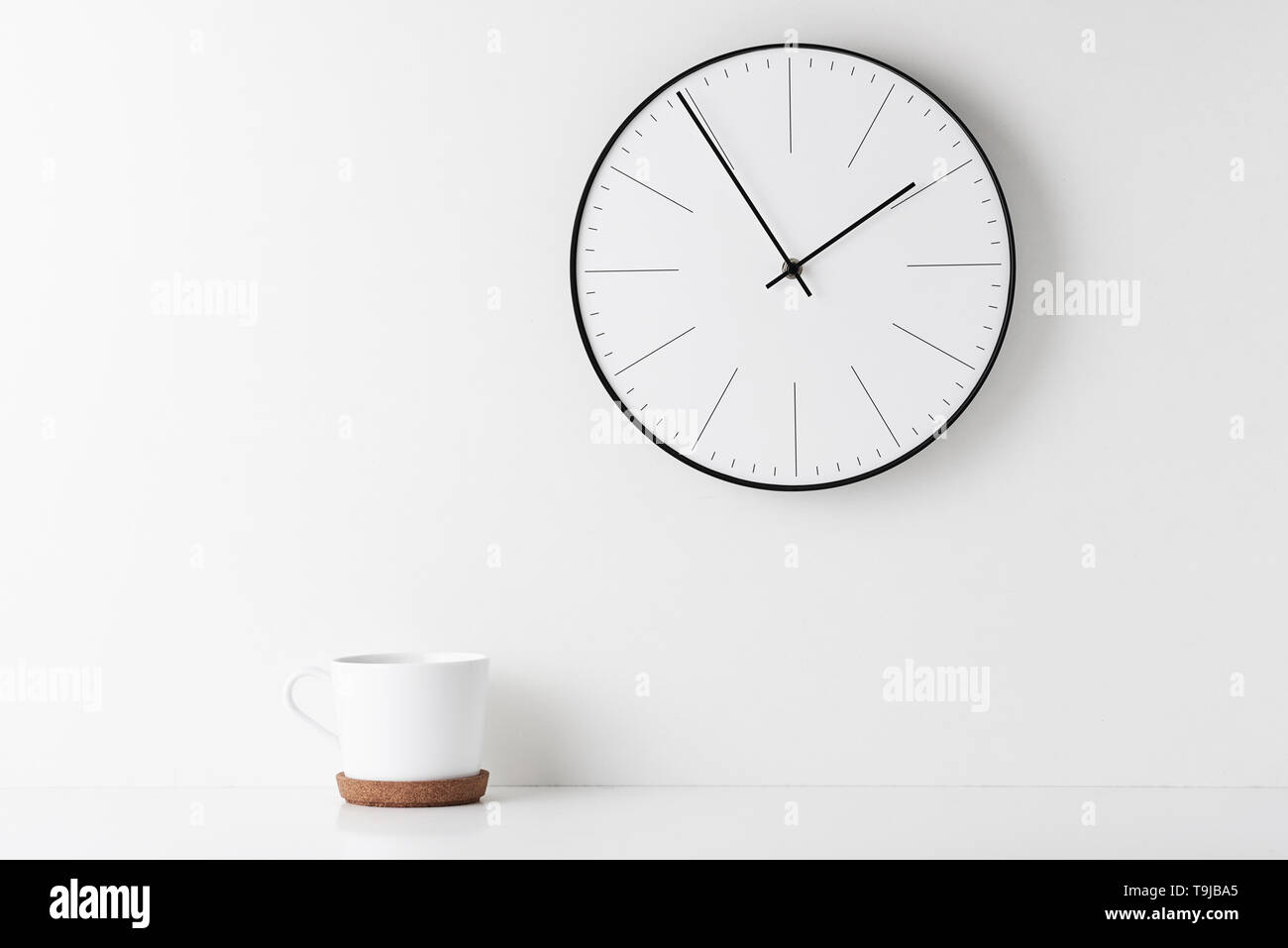 Vue avant 24 avec horloge murale ronde et tasse sur fond blanc. Bureau d'accueil de l'espace minimal 24 Banque D'Images