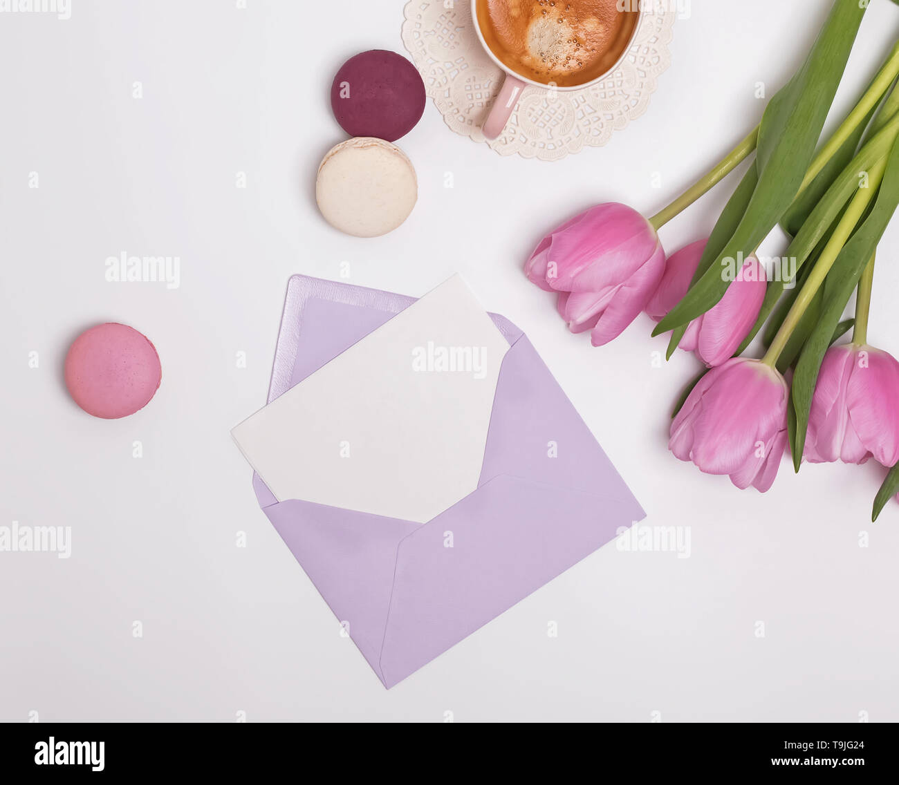 Avec l'enveloppe de papier vierge carte sur la table avec des tulipes roses et café, vue du dessus Banque D'Images