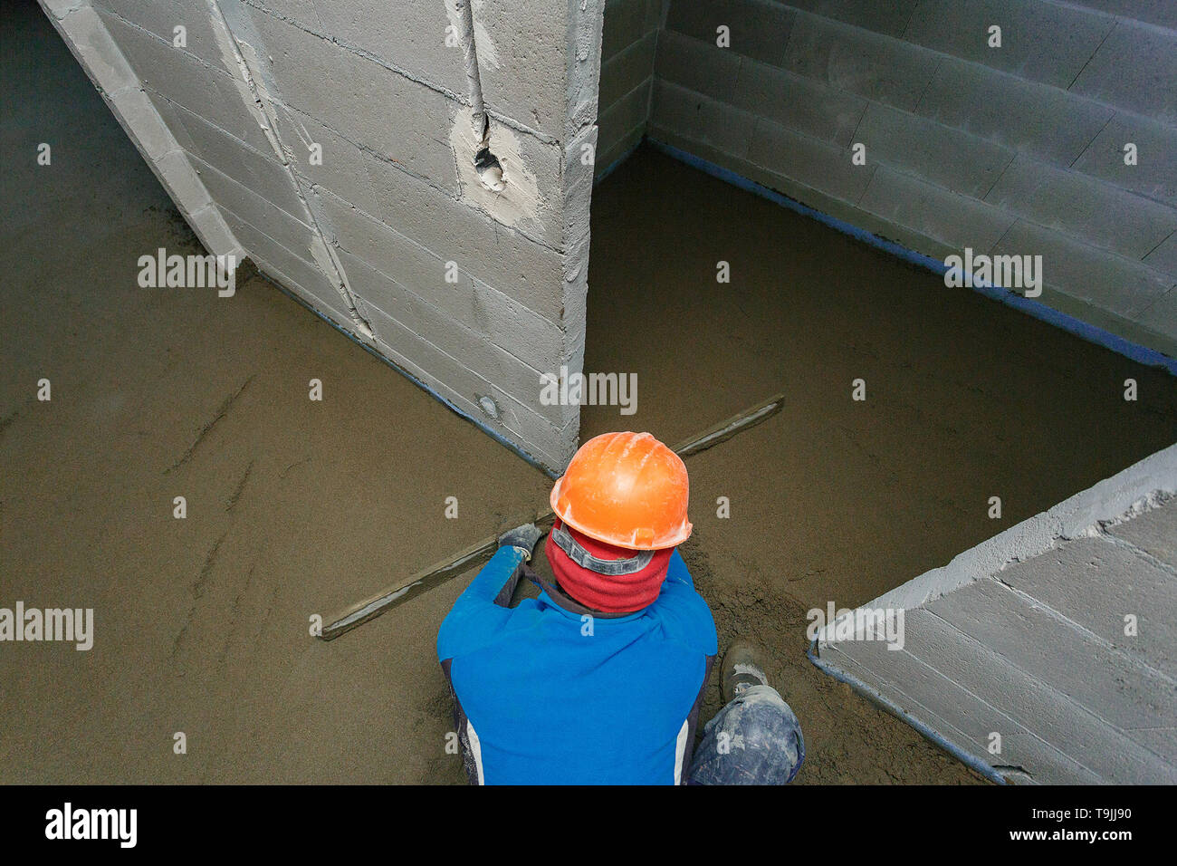 L'ouvrier dans un casque orange est mise à niveau de la chape. Banque D'Images