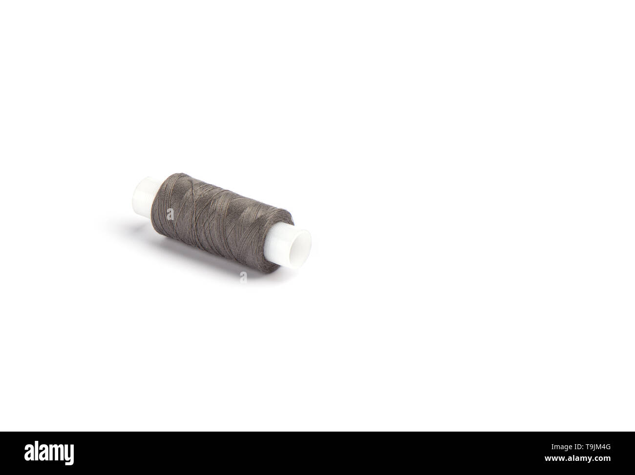 Fils de coton gris clair sur un manchon en plastique pour une machine à coudre. Concept de couture. Copy space Banque D'Images