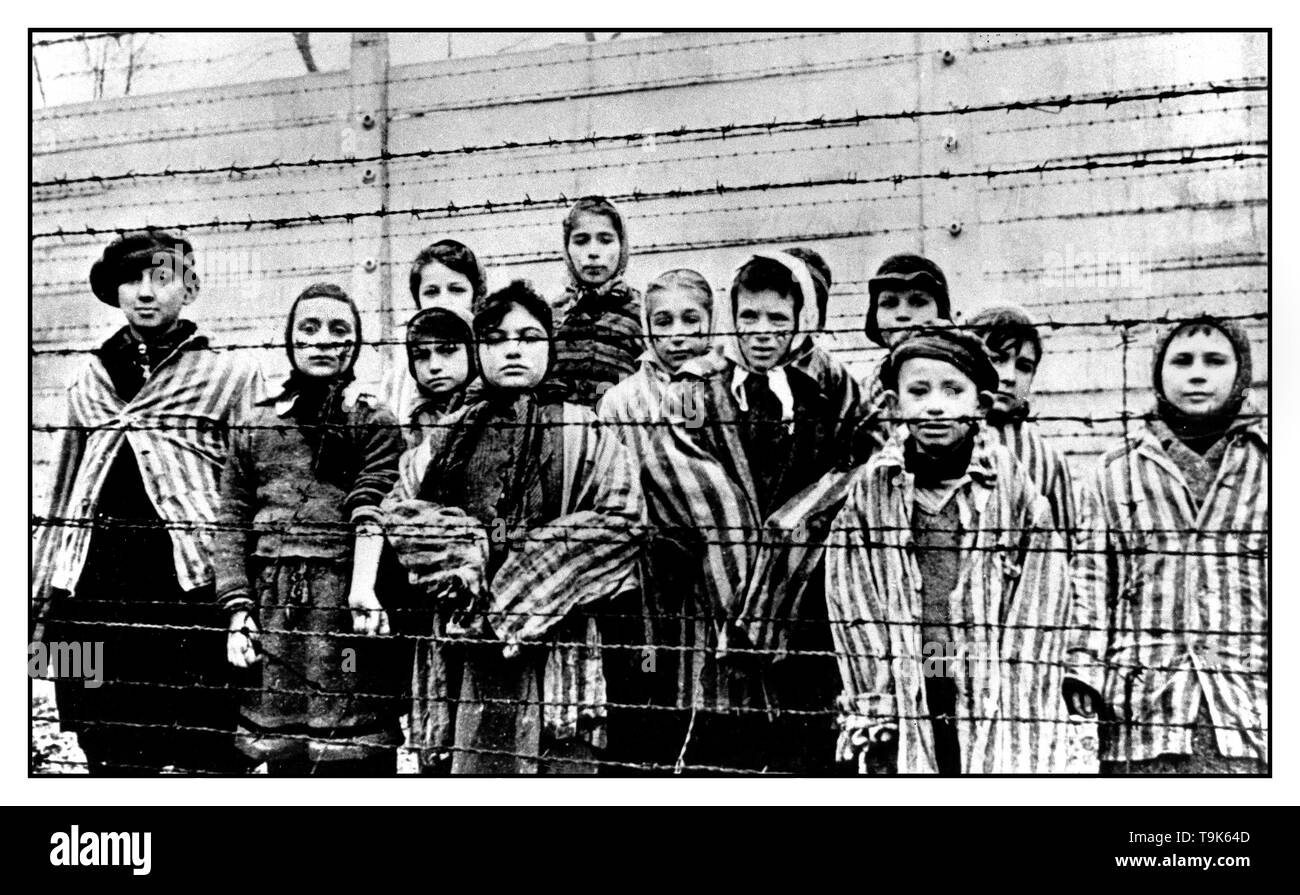 Les enfants d'AUSCHWITZ enfants prisonniers Prisonniers portant des uniformes rayés stare de derrière une barrière de barbelé dans notorious WW2-camp de la mort nazi Auschwitz le sud de la Pologne. Seconde Guerre mondiale Banque D'Images