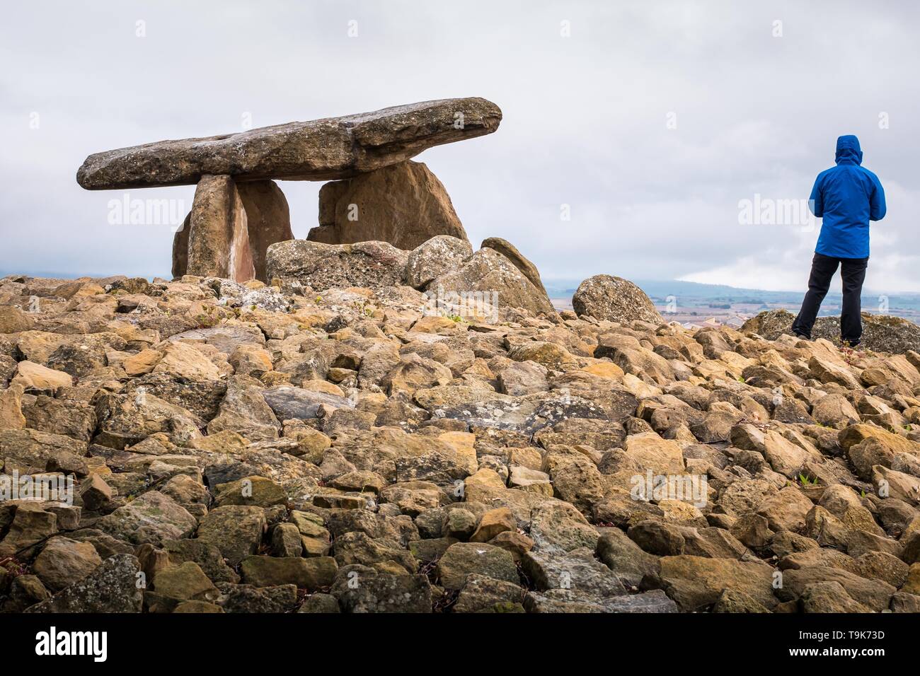 Randonneur vêtues d'un manteau bleu, contemplons le paysage à côté du dolmen 'La Chabola de la Hechicera" (la sorcière Hut) près de Elvillar, Rioja, Espagne Banque D'Images