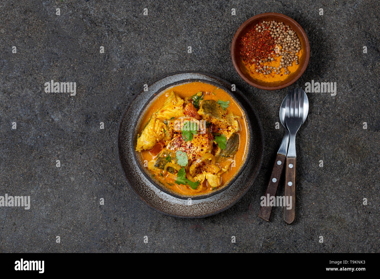 Nourriture indienne. KERALA traditionnel curry de poisson avec du pain naan, gris, plaque de fond noir. Banque D'Images