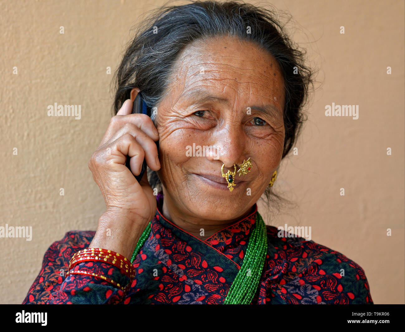 Personnes âgées femme Gurung népalais avec des bijoux de nez passe un appel sur son téléphone cellulaire. Banque D'Images