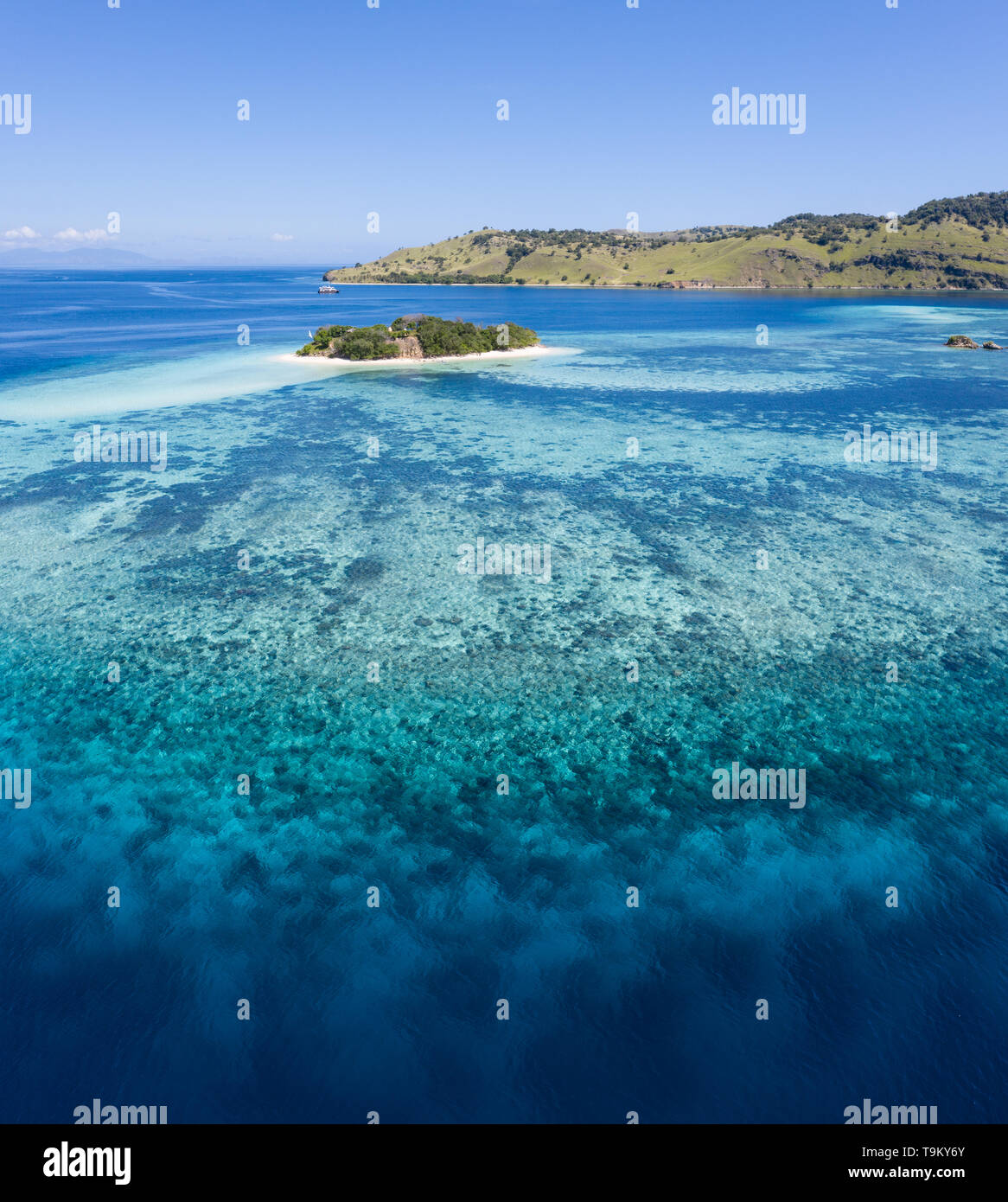 Vu d'une vue à vol d'oiseau, un cadre idyllique île tropicale est entourée d'un récif corallien sain dans le Parc National de Komodo, en Indonésie. Banque D'Images