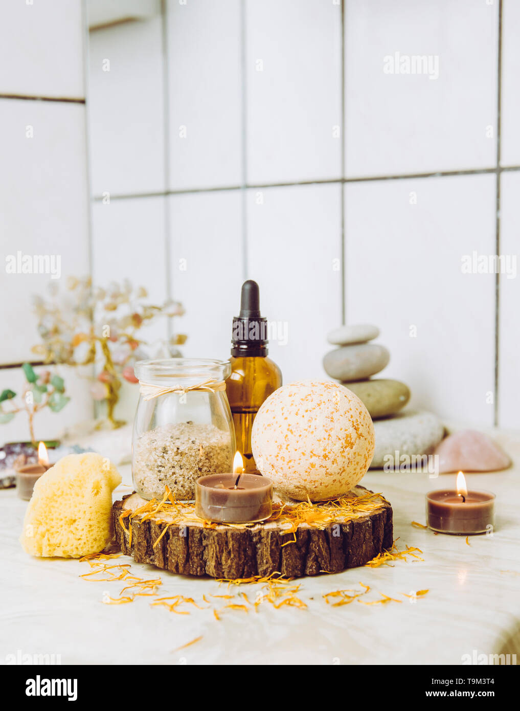 Vue latérale d'accueil produits wellness spa bath bomb orange, arôme, sel de bain, éponge de mer, plateau de bougies allumées. Ensemble très zen, arbre d'amour et de l'améthyste cryst Banque D'Images