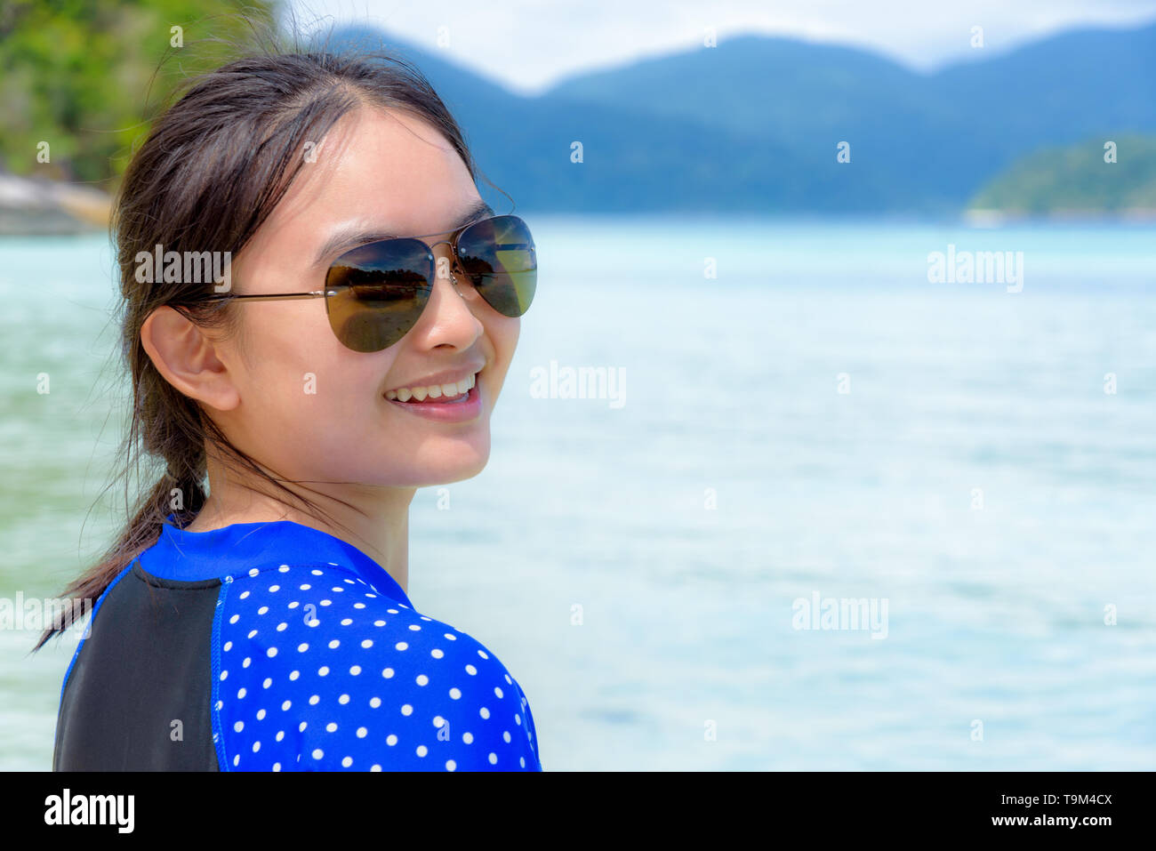 Visage d'une femme portant des lunettes de soleil et sourire à l'appareil photo avec un heureux sur le magnifique paysage naturel de la mer et l'île bac Banque D'Images