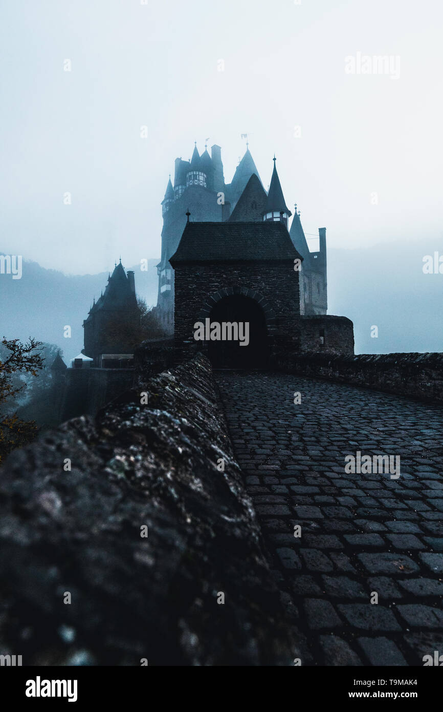 Entrée principale du château Burg Eltz / Eltz avec porte d'entrée historique au cours de l'heure bleue pendant un jour d'automne brouillard brumeux avec château couvert (Allemagne) Banque D'Images