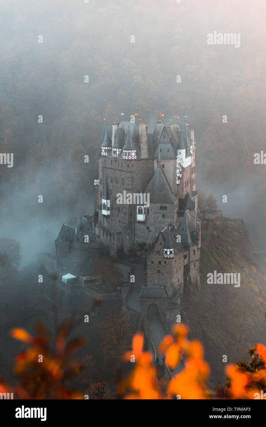 / Burg Eltz Château Eltz pendant le coucher du soleil sur un jour d'automne brumeux d'orangers et de feuilles et le brouillard roulant à travers la vallée (Wierschem, Allemagne) Banque D'Images