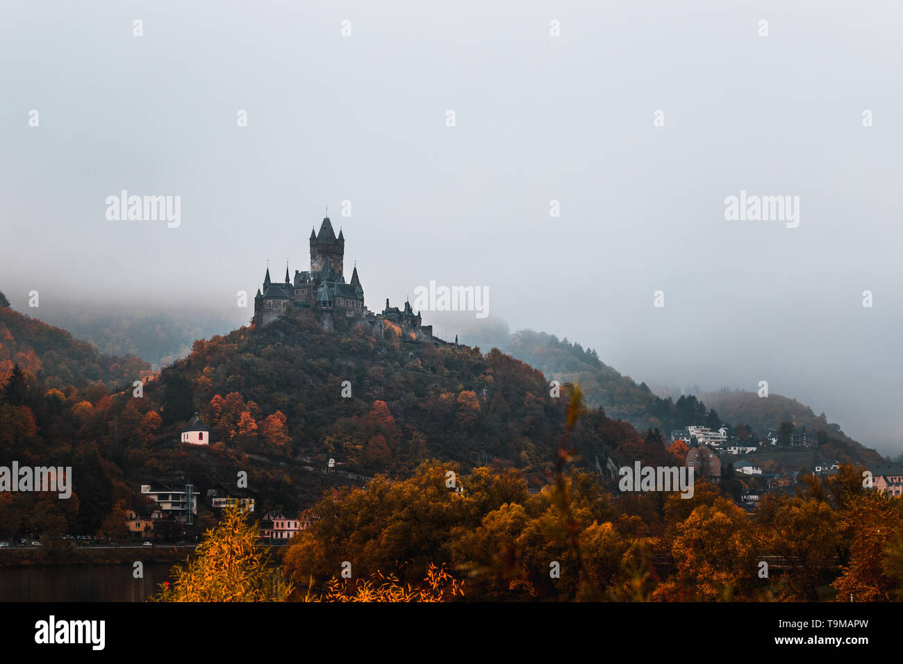 Château Reichsburg Cochem Cochem Castle / couverts dans le brouillard avec Moselle pendant un jour d'automne brumeux avec des nuages bas et des orangers (Cochem, Allemagne) Banque D'Images