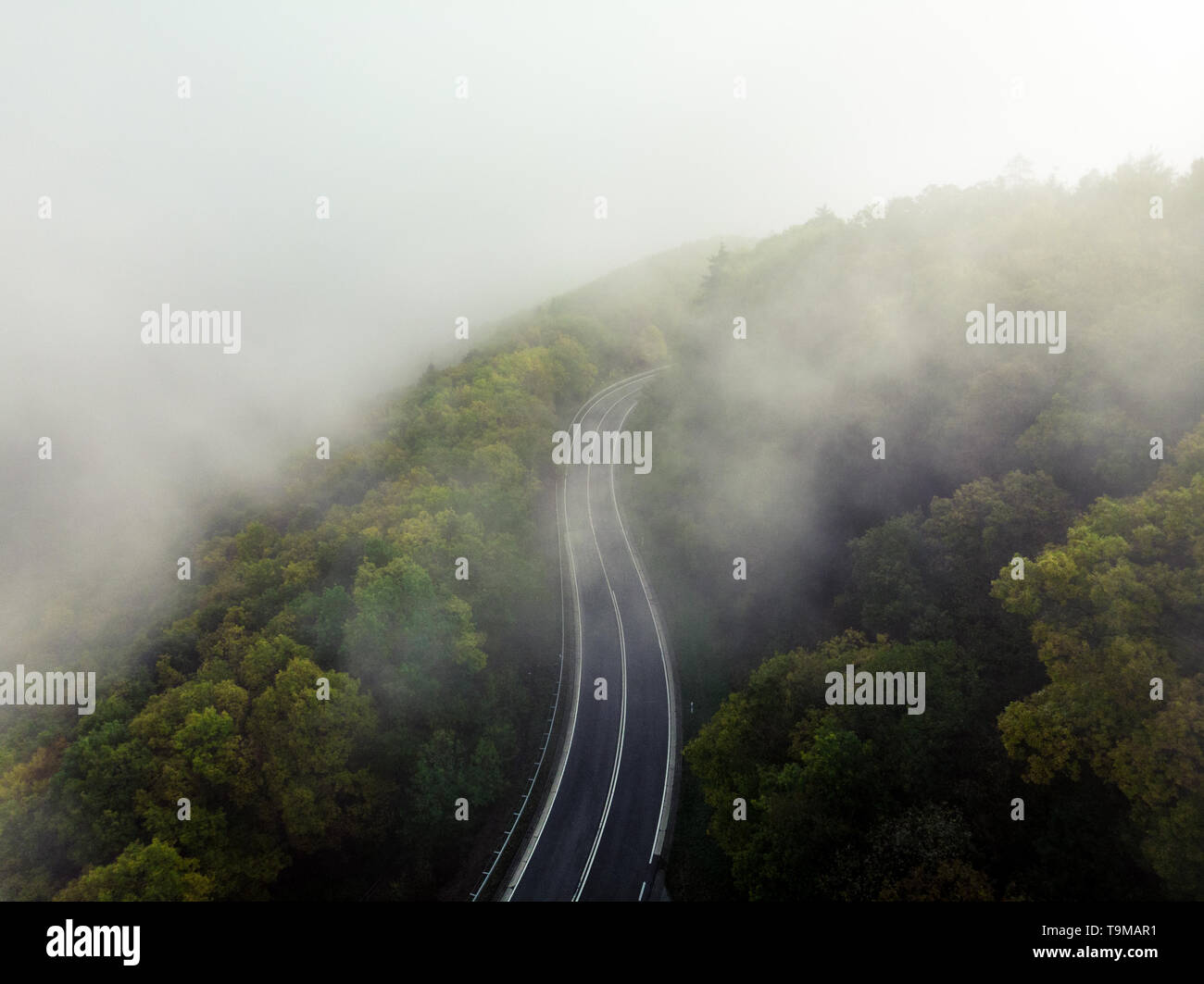 Vue aérienne d'une route de montagne couverte de brouillard dans un écrin de verdure forrest comme repéré par le haut avec un bourdon (Allemagne, Europe) Banque D'Images