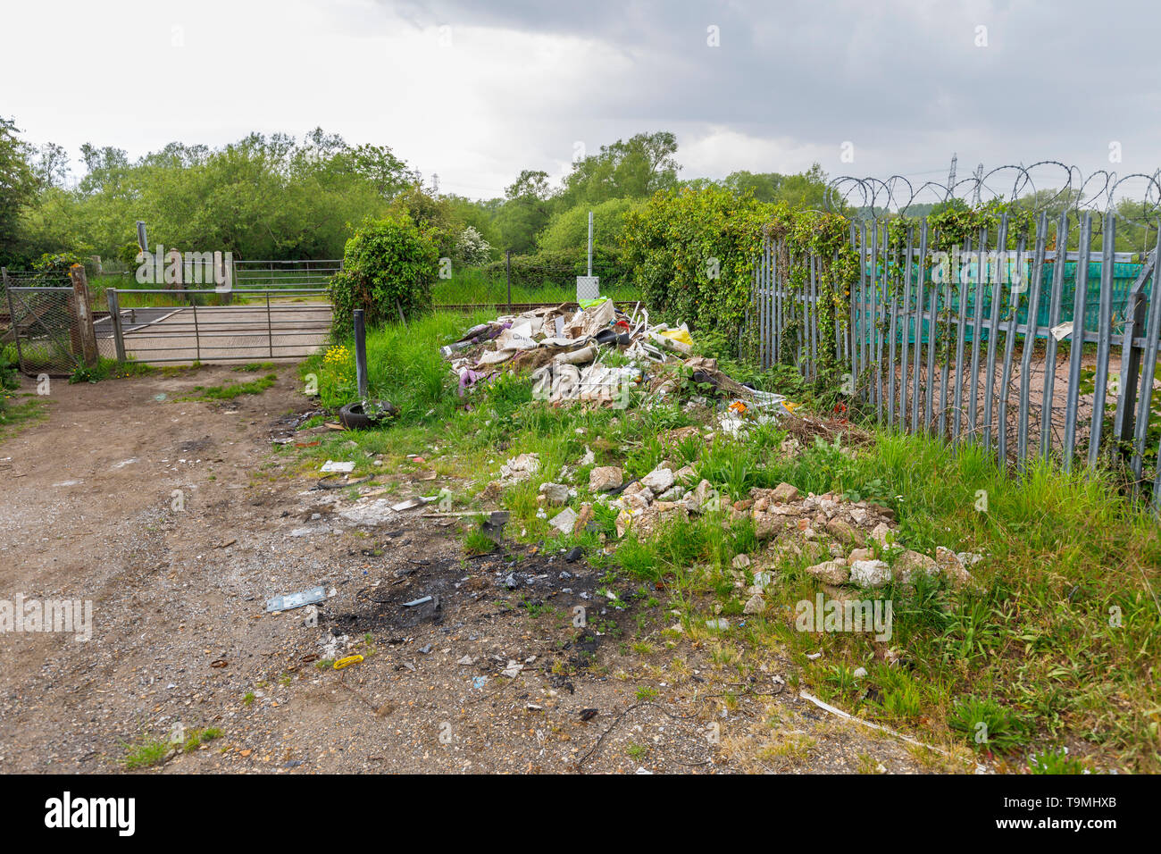 Un tas de détritus, gravats et déchets des sous-évaluées les décharges sauvages illégales à côté d'une ligne de chemin de fer à Nursling, Test Valley, Southampton, Hampshire, Royaume-Uni Banque D'Images