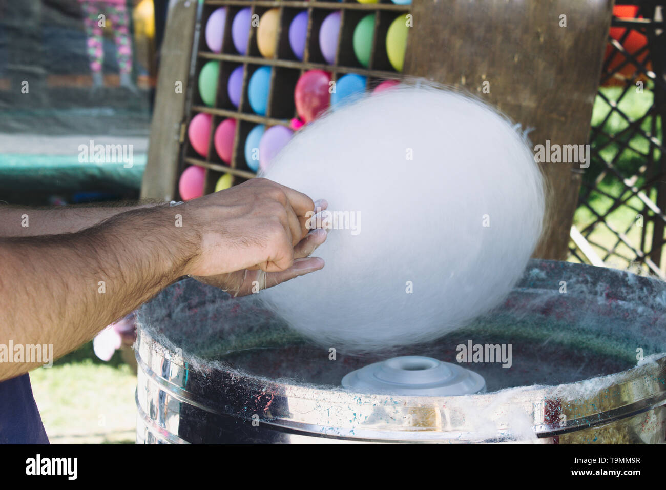 Une main envelopper un Cotton Candy sur un bâton dans une machine à barbe à papa. Faire de la barbe à papa Banque D'Images