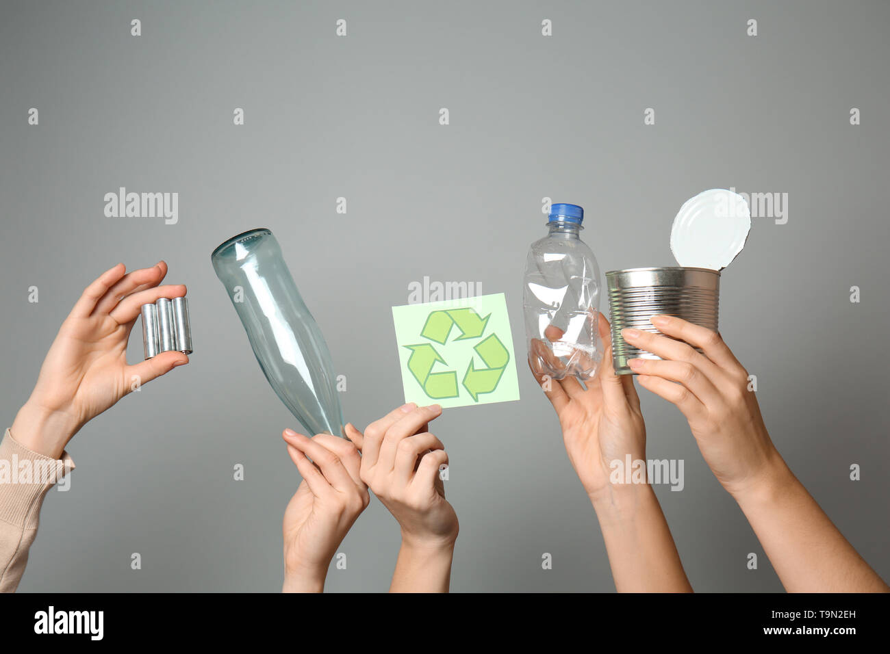 Beaucoup de mains avec différents types de déchets et recyclage symbole sur fond gris. Ecology concept Banque D'Images