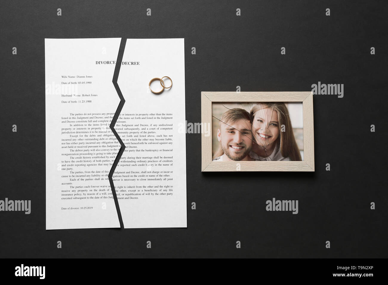 Le jugement de divorce déchirés, bagues et broken frame avec photo sur fond sombre Banque D'Images