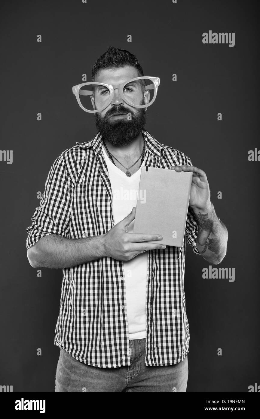 Hipster barbu porter lunettes drôles tenir le bloc-notes ou livre. Jusqu'lumineux votre journée. Lisez ce livre. Comique et l'humour de bon sens. Histoire drôle. Étude est amusant. Banque D'Images