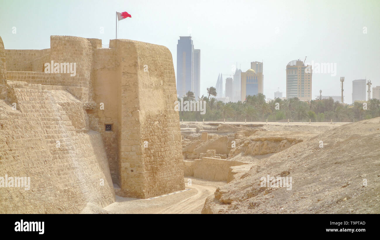 Vu de l'extérieur de la tour de garde, surmontée de l'indicateur et le Bahreïn Manama skyline en arrière-plan, Qalat al Fort, Qal'at al-Bahreïn Banque D'Images