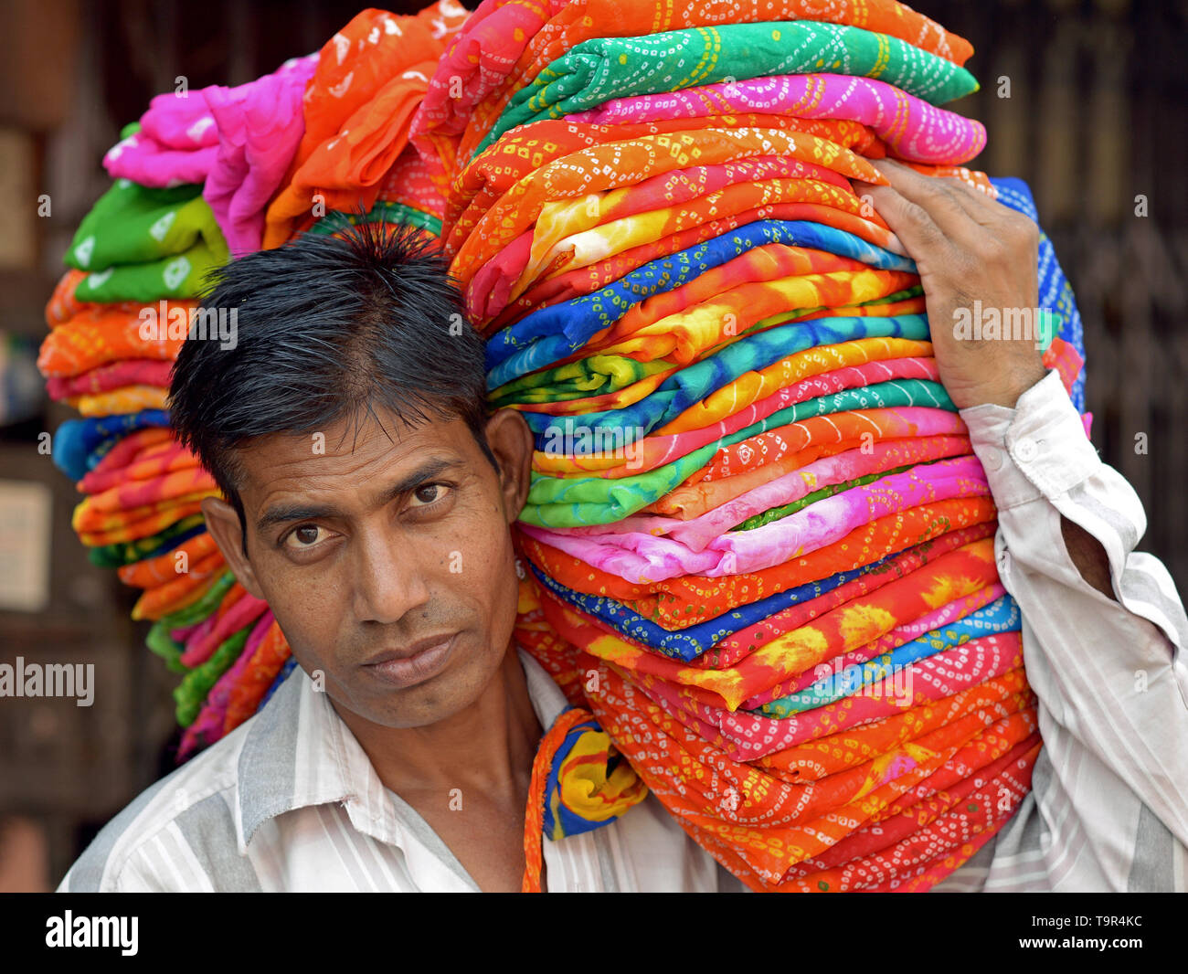 Vendeur indien porte une pile de tissu coloré sur son épaule. Banque D'Images