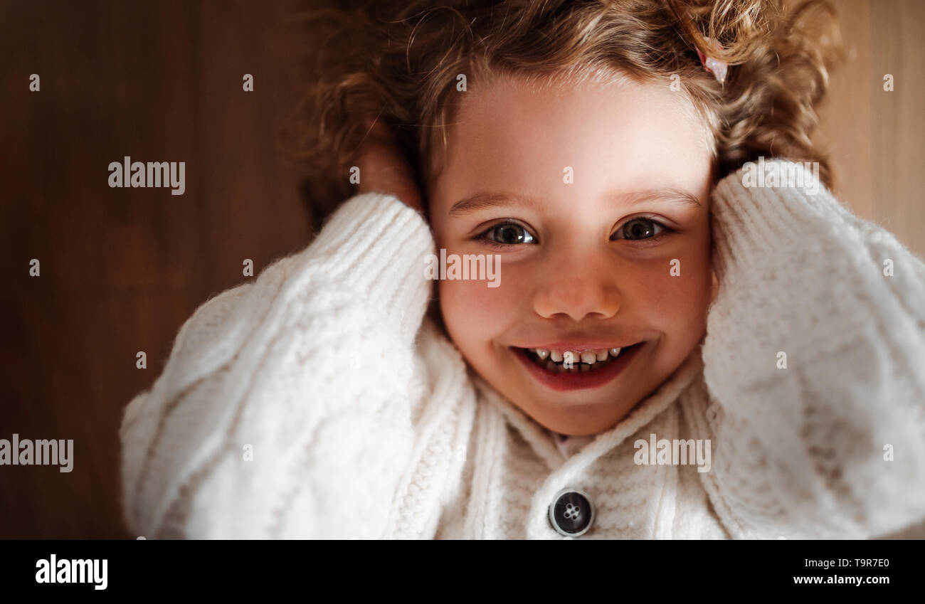 Un portrait de petite fille avec blanc chandail tricoté gisant sur le sol, une vue de dessus. Banque D'Images