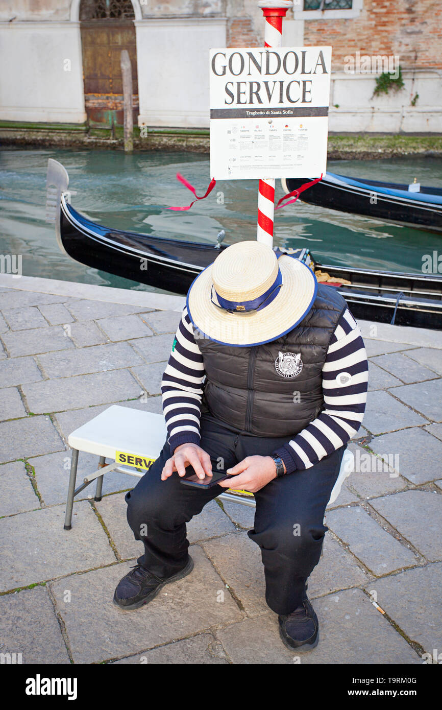 Gondolier texting on his smart phone Banque D'Images