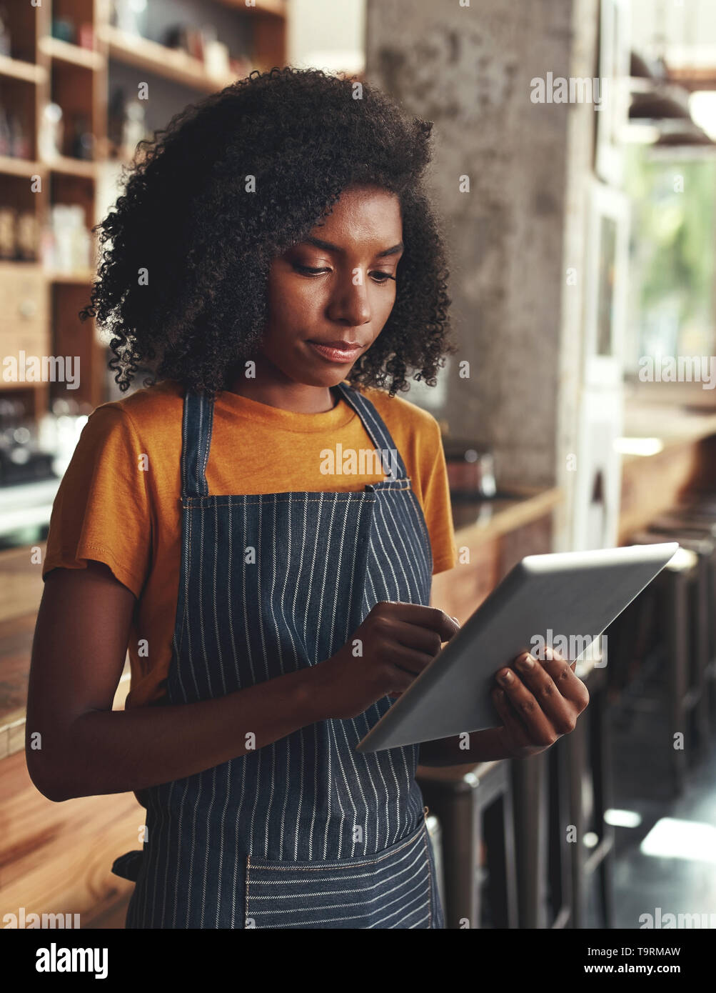 Femme propriétaire using digital tablet au coffee shop Banque D'Images