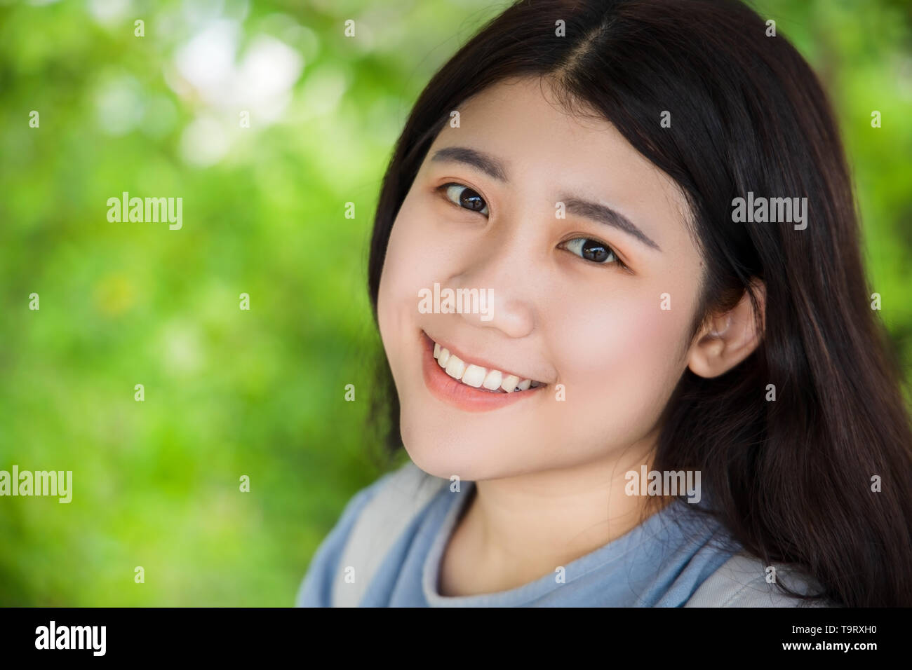 Cute Asian teen girl dodus sain sourire avec belle nature fond vert flou Banque D'Images