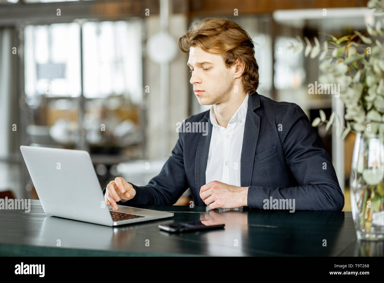 Portrait of a young handsome man portable au bar moderne et spacieuse ou bureau Banque D'Images