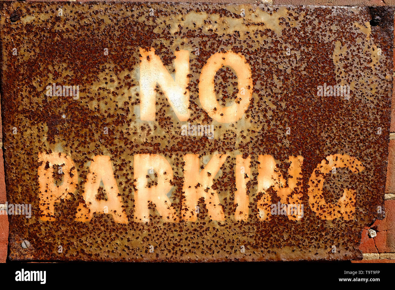 Old rusty metal no parking sign on wall Banque D'Images