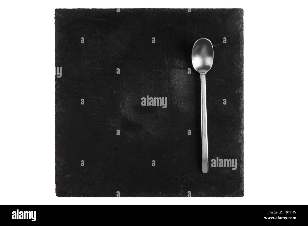 Goutte de miel dans une cuillère en argent et noire sur une tuile en pierre Banque D'Images