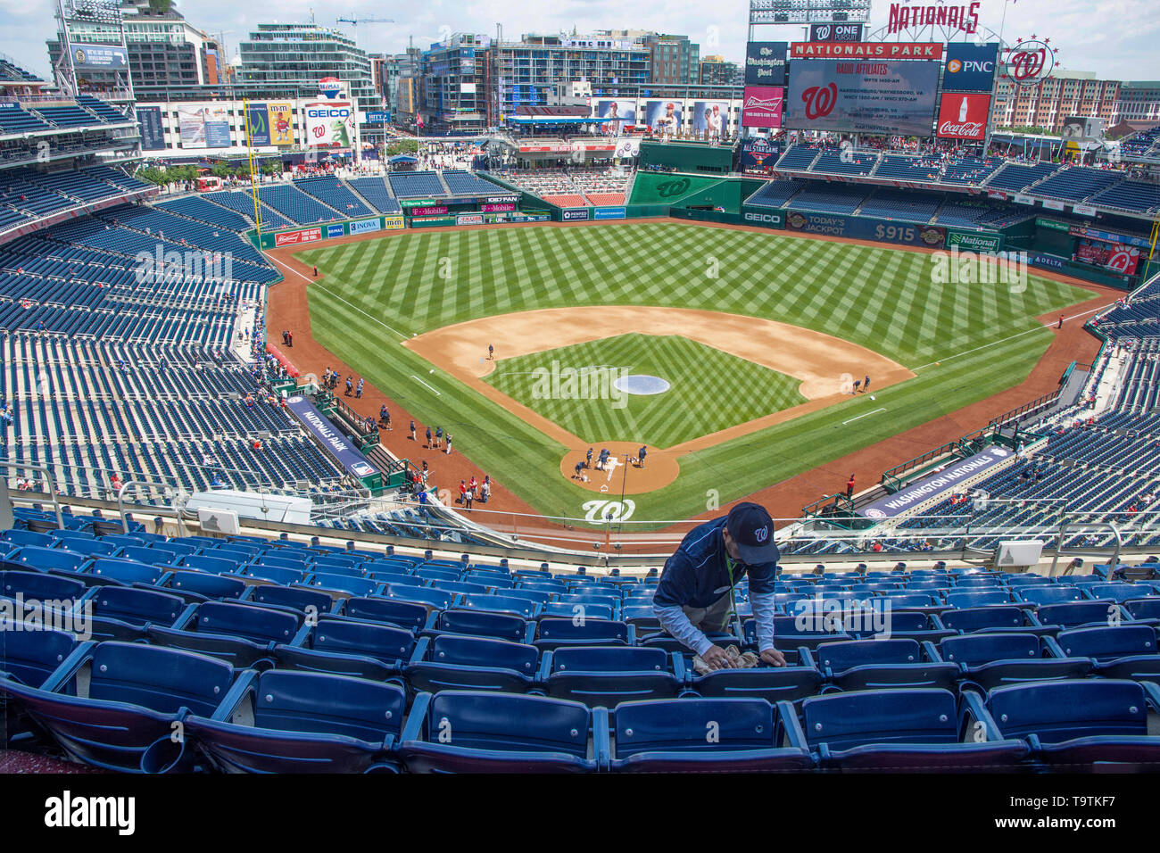 Un huissier nettoie sièges avant le début d'un match de baseball à Washington Nationals Park ressortissants à Washington, DC. Banque D'Images