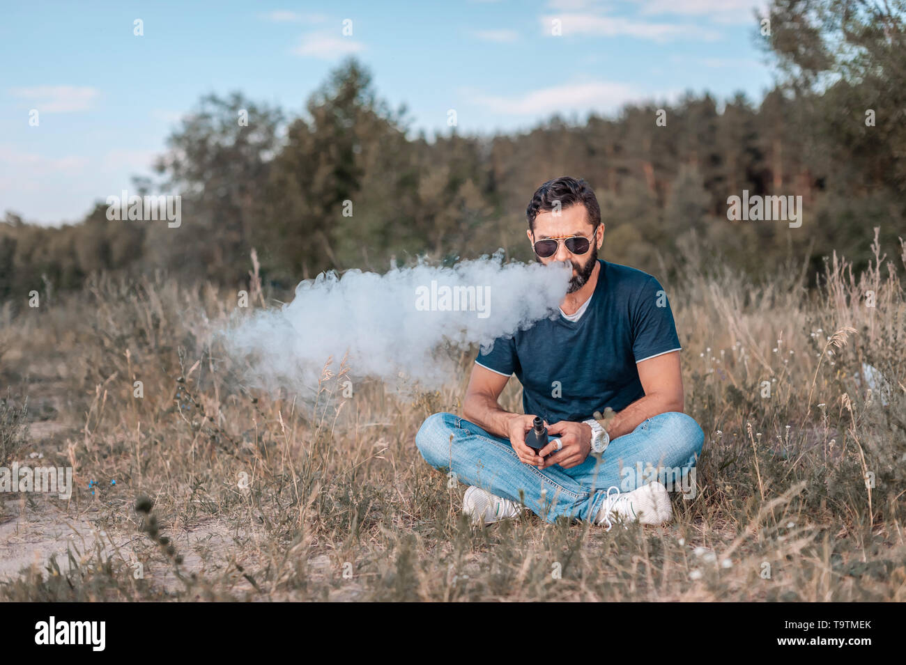 Vape élégant homme bénéficiant d'une fumée à l'extérieur de l'appareil électronique. Vaping concept. Banque D'Images