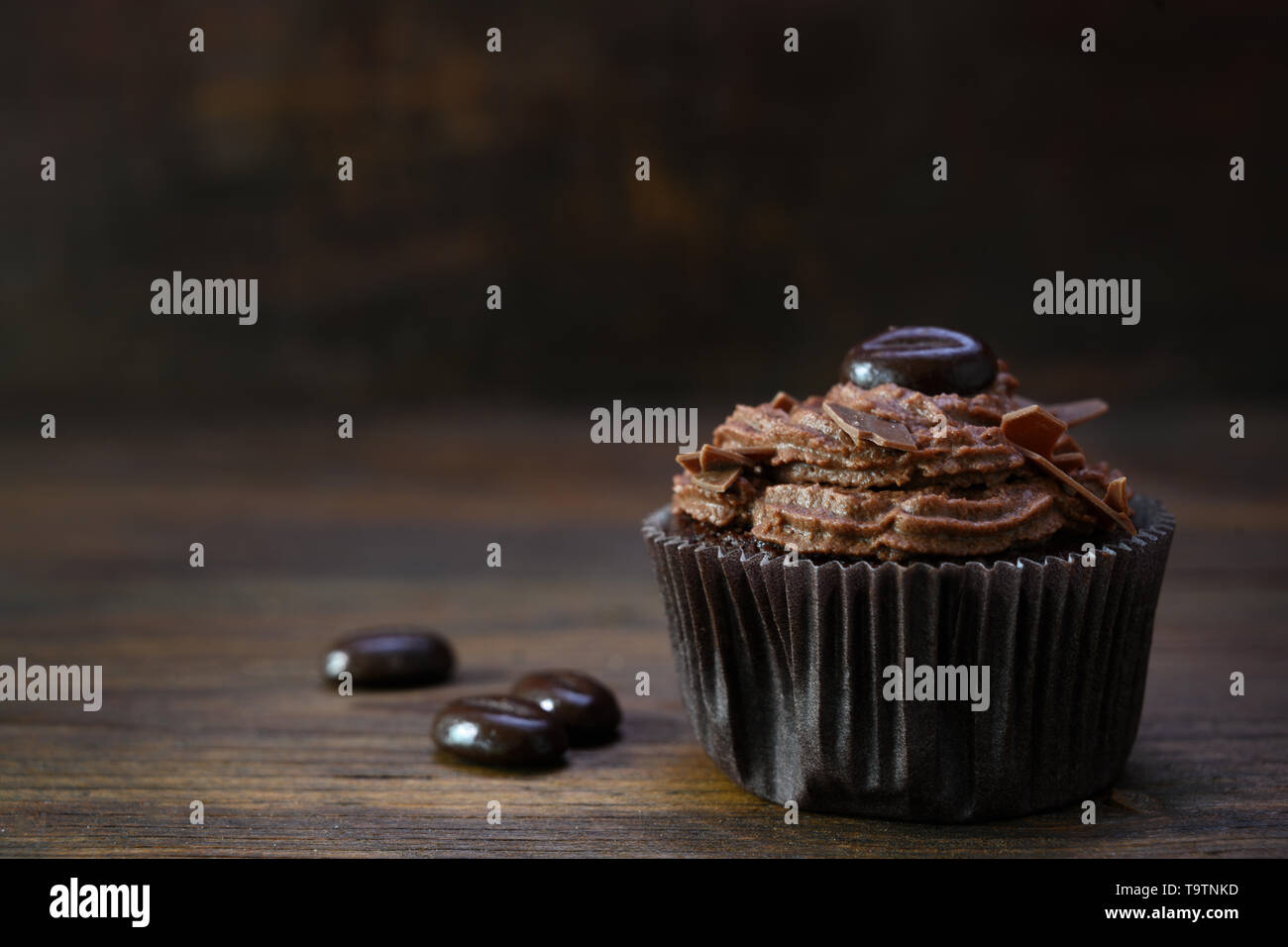 Cupcake marron crème au beurre de cacao, chocolat et café en grains de bois rustique, copie, espace de discussion sélectionné, la profondeur de champ étroite Banque D'Images