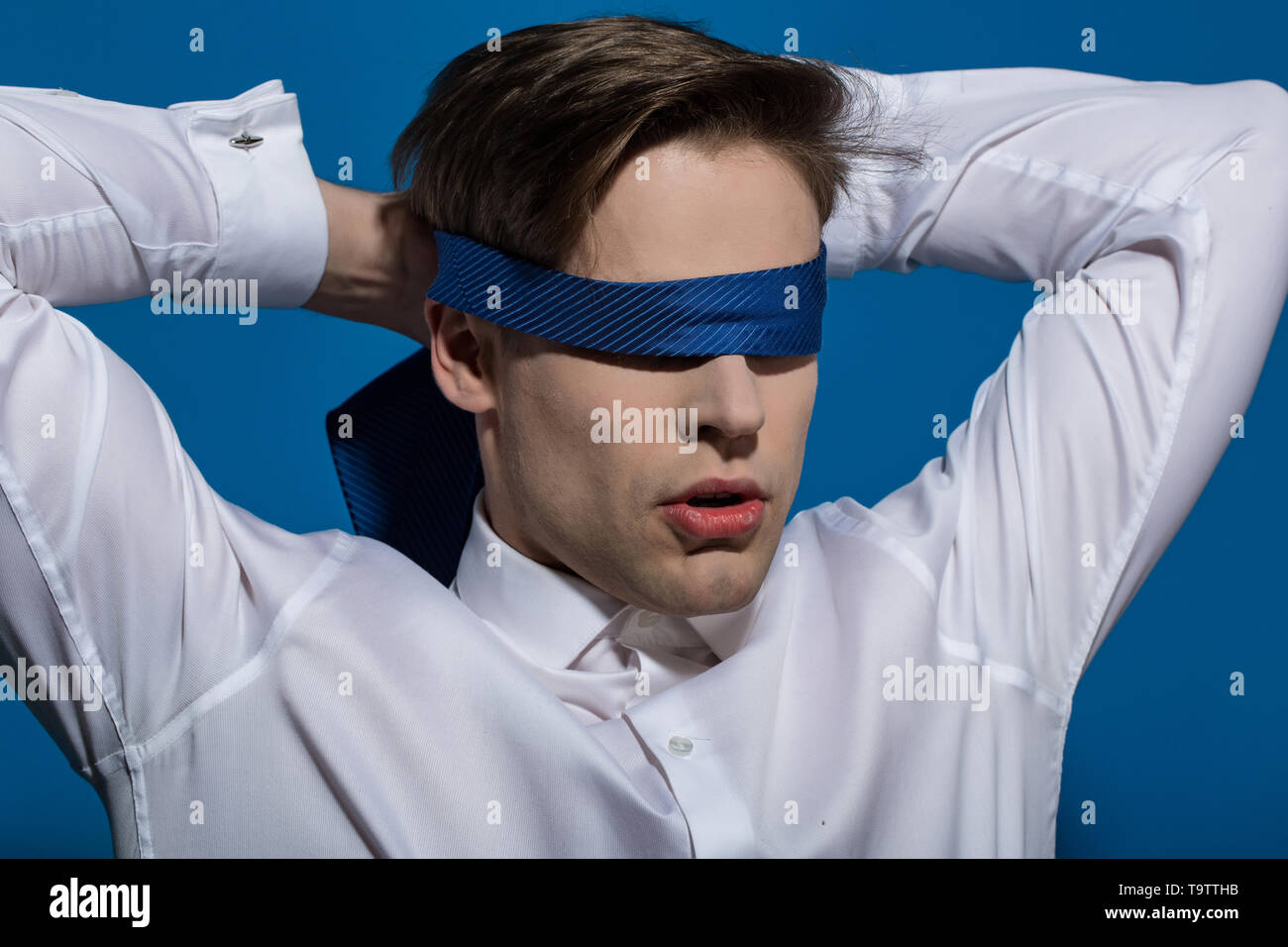 L'homme bandé les yeux avec une cravate sur fond bleu Photo Stock - Alamy