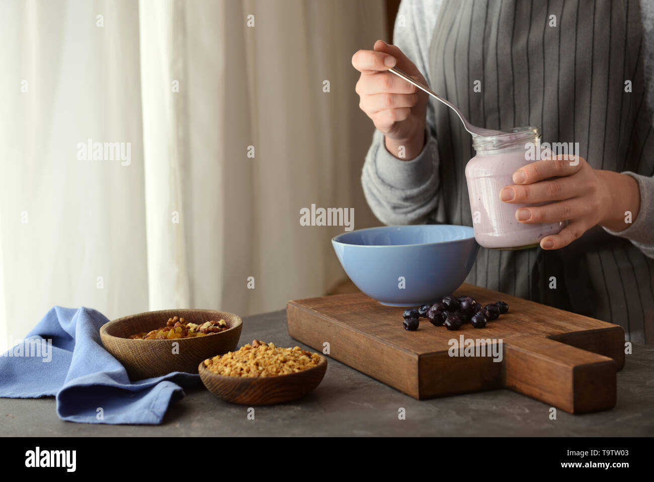 Femme préparant de délicieux muesli in kitchen Banque D'Images