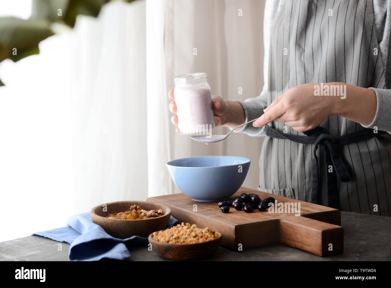 Femme préparant de délicieux muesli in kitchen Banque D'Images